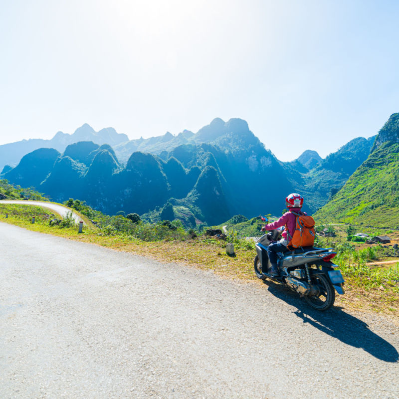 One person riding bike on Ha Giang motorbike loop, famous travel destination bikers easy riders. Ha Giang karst geopark mountain landscape in North Vietnam. Winding road in stunning scenery, travel