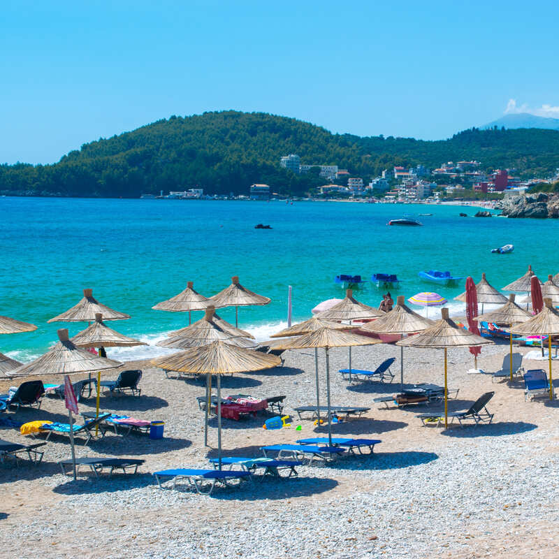 A Sandy Beach Full Of Parasols In Himare, A Coastal Resort Town In The Albanian Riviera, On The Mediterranean Sea, Albania, South Eastern Europe