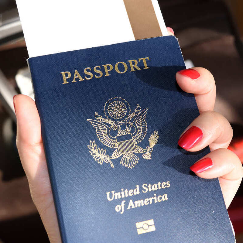 Female Traveler With Nails Painted Red Clutching A U.S. Passport
