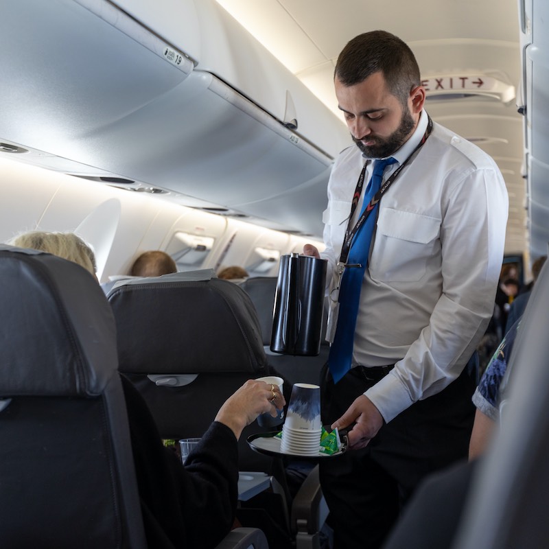 flight attendant pouring coffee for passenger