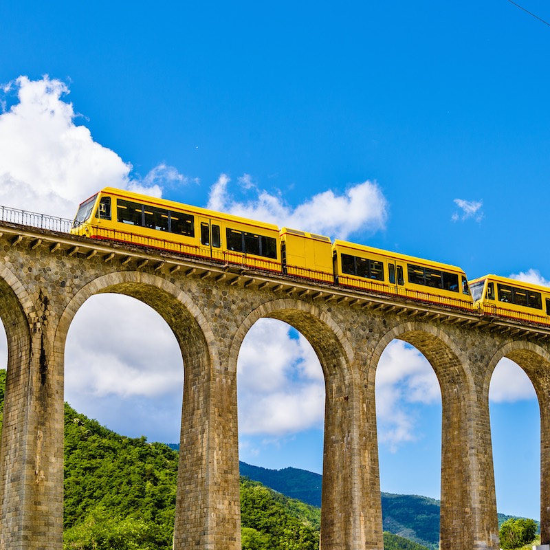 yellow train over bridge in the south of France