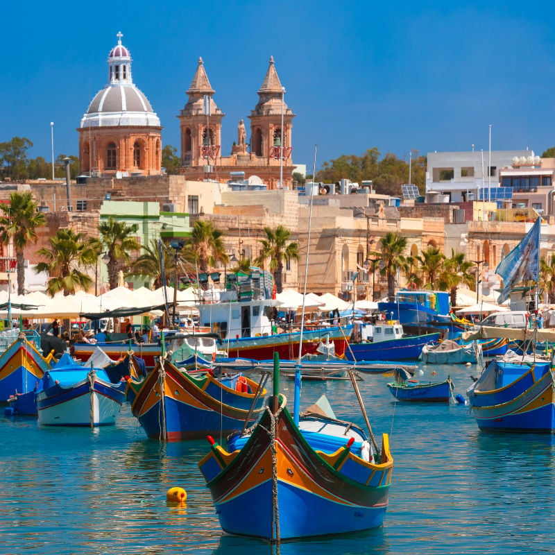Traditional eyed colorful boats Luzzu in the Harbor of Mediterranean fishing village Marsaxlokk, Malta