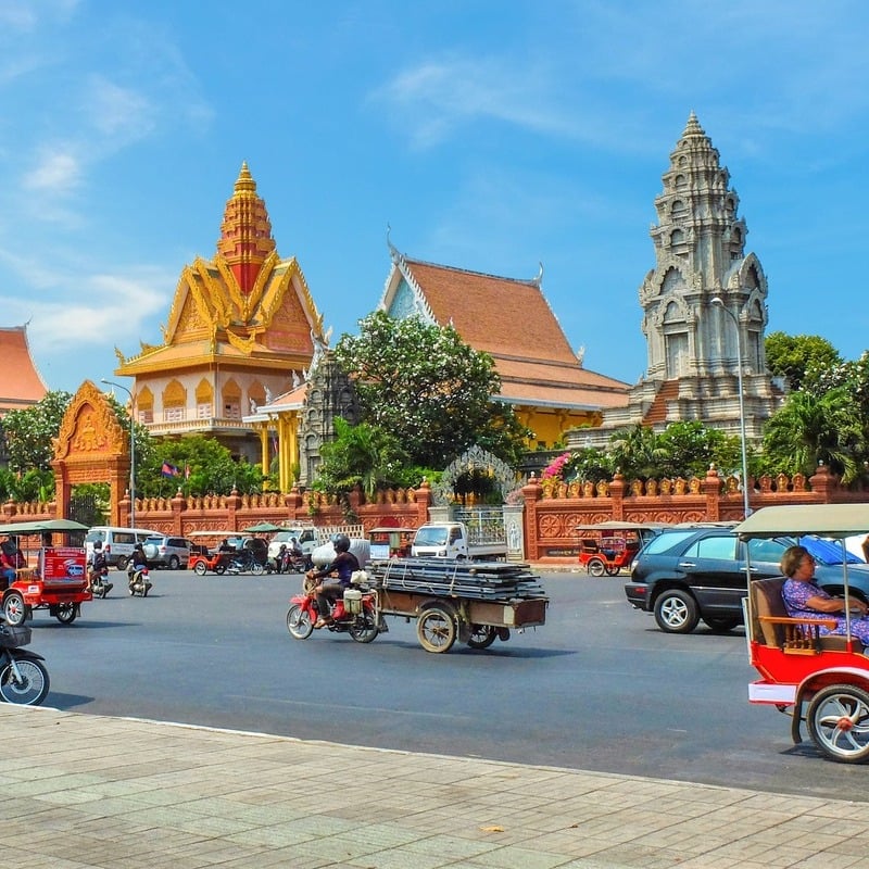 A Busy Road And Ancient Temples In Phnom Penh, Capital City Of Cambodia, Southeast Asia