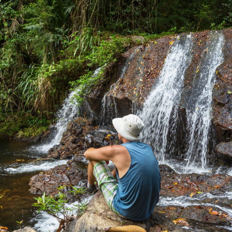 Man Resting By Waterfall In Jungle In Belize, Central America