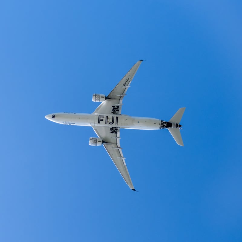 fiji airways plane flying overhead in blue sky