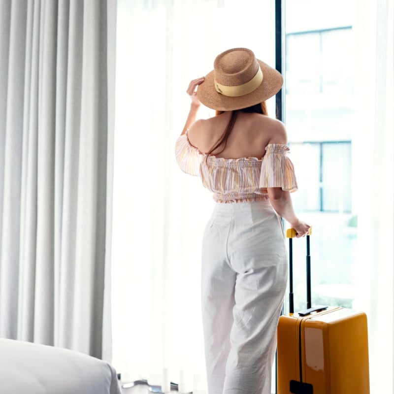 woman standing in hotel with suitcase