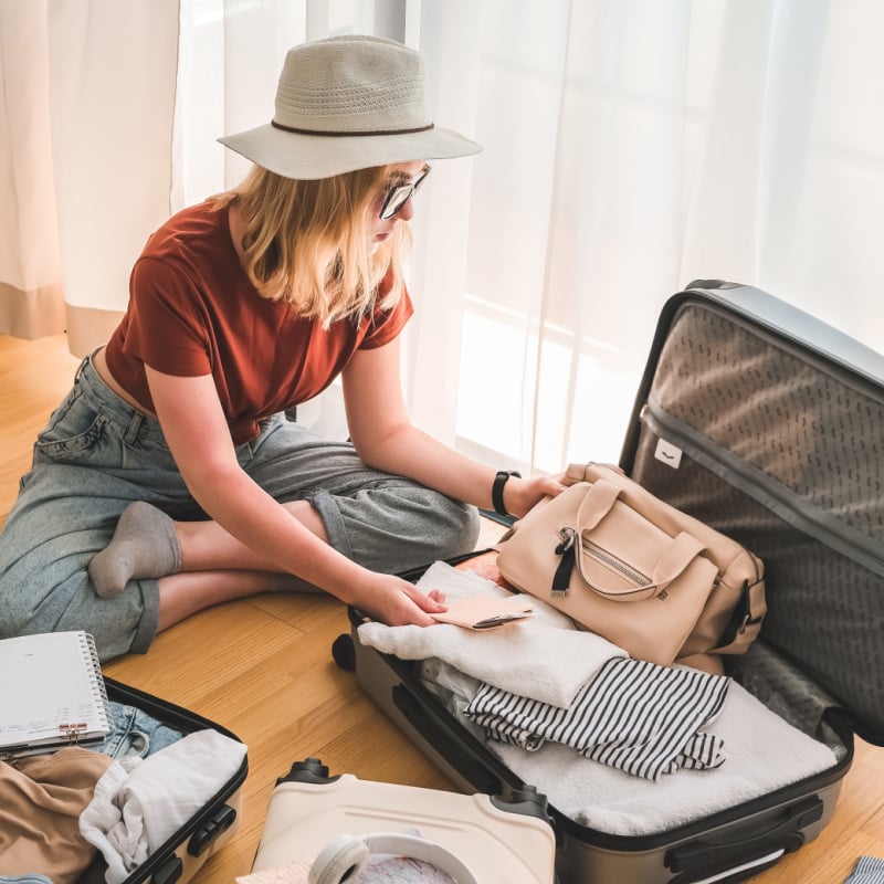 female solo traveler packing a suitcase at home